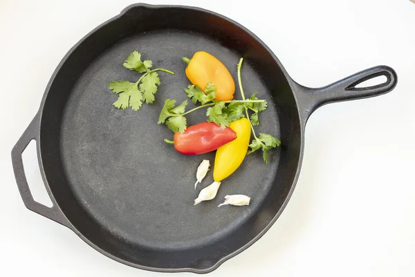 Чугунная сковорода с красным, желтым и оранжевым перцем, петрушка — стоковое фото
