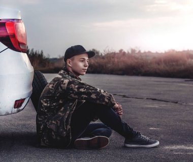car yakınındaki yolda akşam oturan genç adam