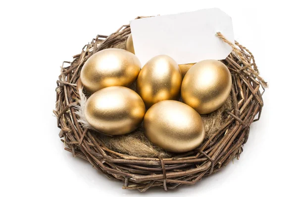 Φωλιά με χρυσά αυγά με ένα tag και ένα μέρος για κείμενο σε λευκό φόντο. Η έννοια της επιτυχημένης συνταξιοδότηση — Φωτογραφία Αρχείου