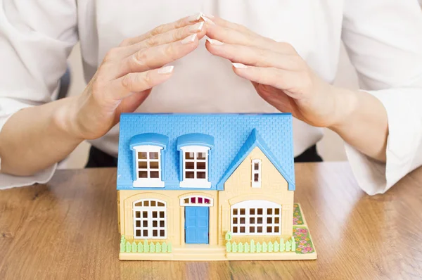 Frau hält schützende Hände über ein Haus — Stockfoto