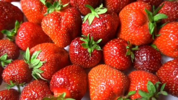 Rote reife Gartenerdbeeren, Rotation der Beeren auf weißem Tisch, schöner Hintergrund — Stockvideo