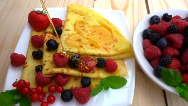 Honey pours on pancakes with raspberries, blueberries and strawberries, slow motion — Stock Video