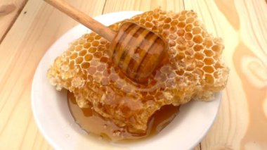 Bal ayı petek üzerinde gelen sarı arka plan üzerinde damlayan tatlım. ağır çekim