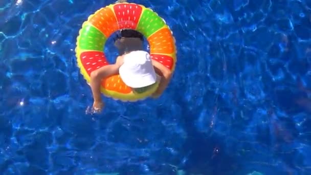 El niño nada en la piscina con un círculo inflable, cámara lenta — Vídeo de stock