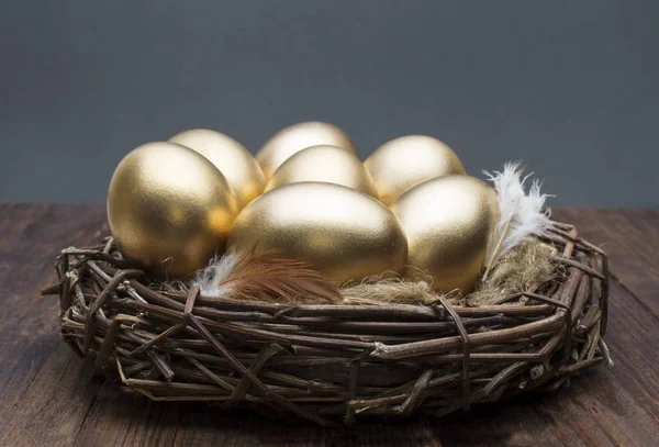Ninho com ovos dourados em um fundo de madeira. O conceito de aposentadoria bem sucedida — Fotografia de Stock