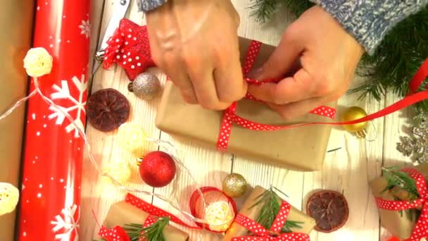 Mujer está envolviendo regalos de Navidad sobre la mesa, concepto de preparación para el Año Nuevo y las vacaciones de Navidad — Vídeos de Stock