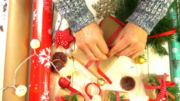 Mulher está embrulhando presentes de Natal na mesa, conceito de se preparar para o Ano Novo e feriados de Natal — Vídeo de Stock