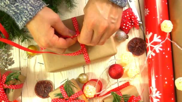 Mulher está embrulhando presentes de Natal na mesa, conceito de se preparar para o Ano Novo e feriados de Natal — Vídeo de Stock