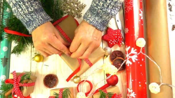 Женщина заворачивает рождественские подарки на стол, концепцию подготовки к новогодним и рождественским праздникам — стоковое видео