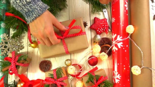 Γυναίκα είναι συσκευασία χριστουγεννιάτικα δώρα στο τραπέζι, έννοια της προετοιμασίας για την Πρωτοχρονιά και τα Χριστούγεννα διακοπές — Αρχείο Βίντεο