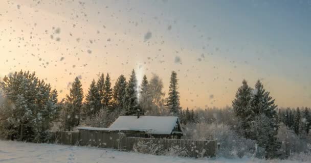 Una pequeña cabaña de troncos cerca del bosque, una hermosa nevada al atardecer, un hermoso paisaje invernal. lazo de vídeo, cinemagrapf — Vídeos de Stock