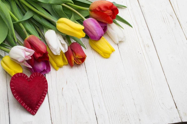 Ramo de tulipanes y corazón rojo sobre tabla de madera rústica, día de la mujer, día de San Valentín , — Foto de Stock