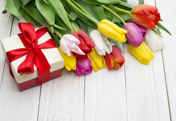 Ramo de tulipanes con un regalo sobre tabla de madera rústica — Foto de Stock