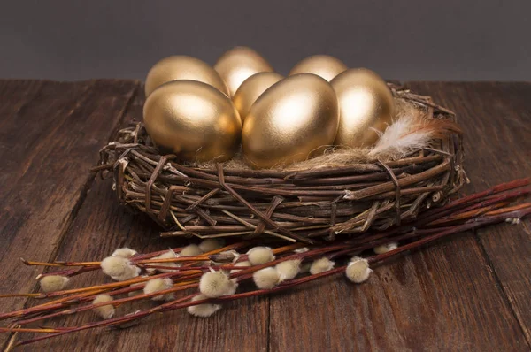 Ninho com ovos dourados com salgueiro em um fundo de madeira. Páscoa . — Fotografia de Stock