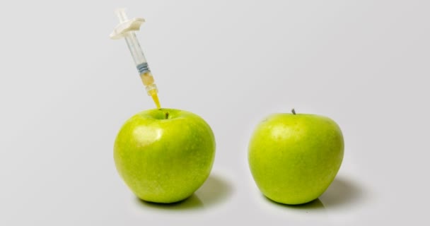 A fresh apple with a syringe and a decaying apple during, time laps, the concept of slowing down aging using medical and chemical methods — Stock Video