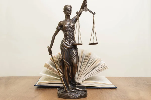 Statue der Gerechtigkeit auf Holztisch vor dem Hintergrund eines offenen Buches — Stockfoto
