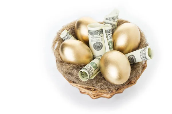 Hnízdo s zlatá vejce na bílém pozadí. Zlatá vejce v hnízdě s dolarů — Stock fotografie