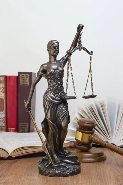 Estátua de justiça na mesa de madeira contra o fundo de um livro aberto . — Fotografia de Stock