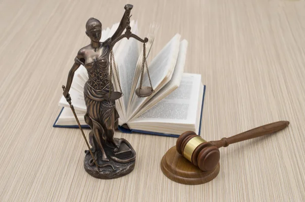 Estátua de justiça na mesa de madeira contra o fundo de um livro aberto . — Fotografia de Stock
