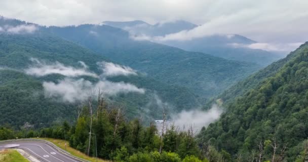 El inicio del crepúsculo en las montañas y la aparición de niebla en una serpentina de montaña, el tiempo de la noche de montaña caducan con las luces de un vehículo de paso rápido en la niebla — Vídeo de stock