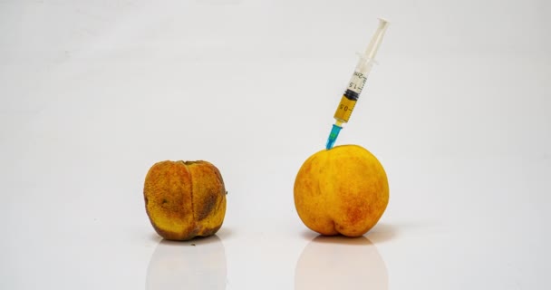 白色背景上的两个桃子，其中之一是腐烂、时间流逝、通过身体的医疗干预使产品年轻化和保存的概念 — 图库视频影像