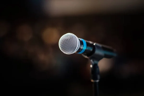 Cool mic on a stand in front of the concert hall, beautiful blurred dark background with a copy space for a message.