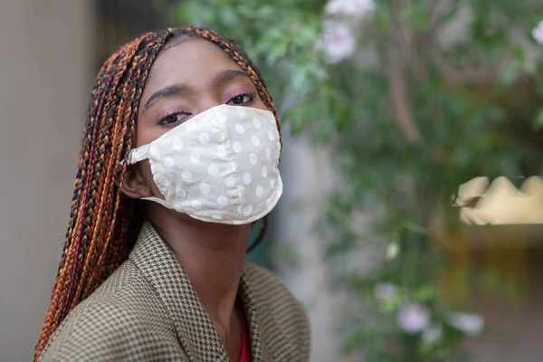 Young dark-skinned girl wearing protective fabric face mask in coronavirus pandemic, COVID-19.