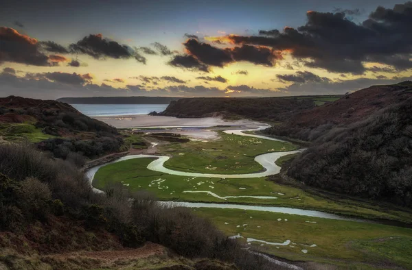 Penmaen, Gower, Swansea, İngiltere'de Three Cliffs Bay ve The Great Tor'da nehrin üzerinde akşam gökyüzü