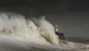 Porthcawl lighthouse and pier in the jaws of a storm on the coast of South Wales, UK. clipart