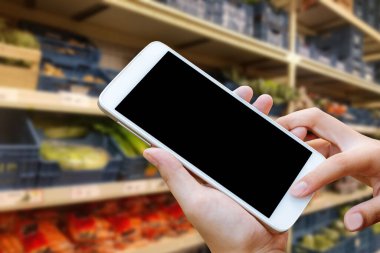 Kadın el ele tutuşup ekrandaki akıllı telefona ya da cep telefonuna dokunmak bulanık alışveriş merkezi ya da süper market geçmişi.