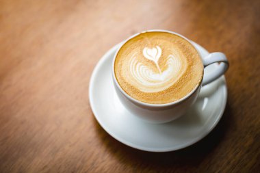 Ahşap masa arkasında beyaz bir fincan geç kalmış sanat kahvesi..