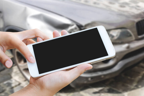 женщина держит в руках и сенсорный экран смартфона или мобильного телефона на размытом фоне автомобильной аварии
.
