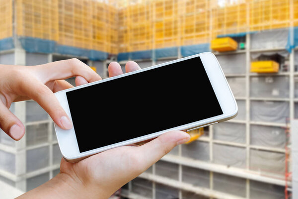 женщина держит и сенсорный экран смартфона или мобильного телефона на размытом фоне строительства здания
, 