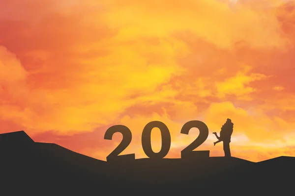 背景がぼやけている空を背景に2021年のテキストを持つミニチュアカップルのシルエット — ストック写真