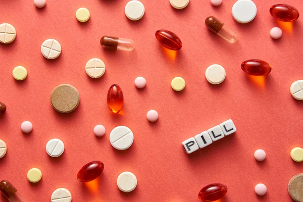 Black and white title PILL from white cubes on the table with tablets on coral background