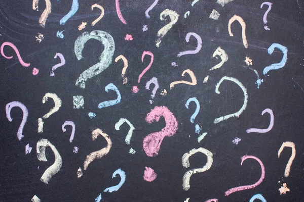 Multicolored question marks are painted with chalk on a blackboard.uncertainty or doubt concept