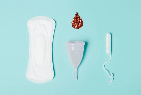 Тампон, прокладка, менструальная чашка с каплей крови на синем фоне — стоковое фото