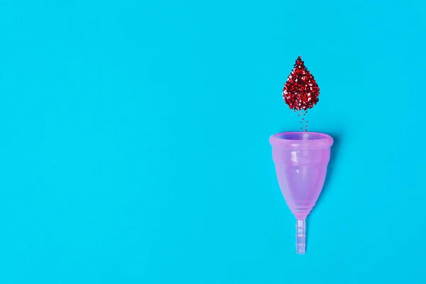 Cangkir menstruasi pink dengan setetes darah pada latar belakang biru . — Stok Foto