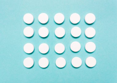 Yuvarlak, mavi arka planda beyaz haplar. Hastalığın tedavisi, sağlık sigortası, eczacılık konsepti.