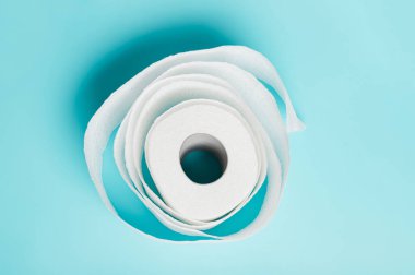 Mavi arka planda yumuşak beyaz tuvalet kağıdı rulosu. Temizlik, temizlik kavramı.