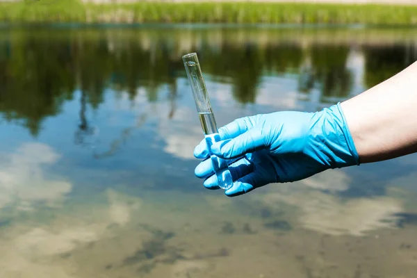 Eldivenli el test tüpünde su topluyor. Ekoloji, çevre kirliliği kavramı