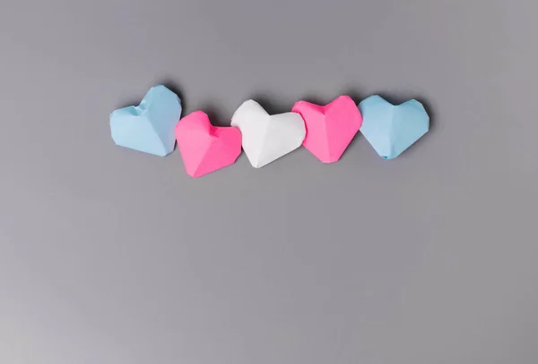 Gri arkaplanda transgender bayrak renginde Origami kağıt kalpler
