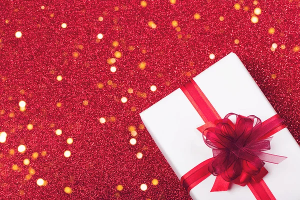 White box with a red ribbon on a festive brilliant background