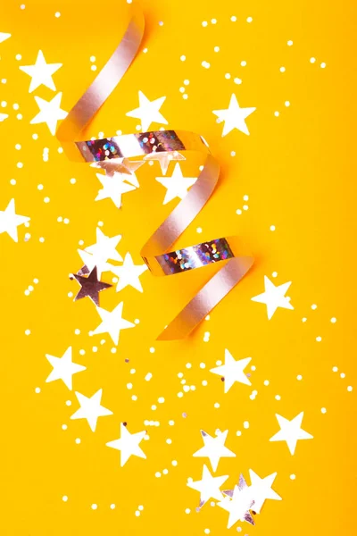 Shiny party streamers and stars on the hot orange background