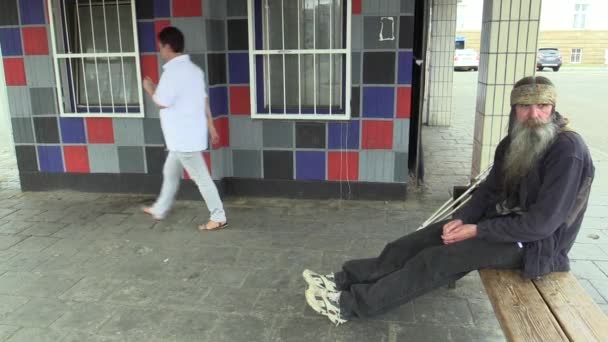 市、長いひげと髪、社会の瀬戸際に貧乏人にインド スカーフで本格的な感情顔ホームレス男がベンチと無効な松葉杖に座ってオロモウツ、チェコ共和国、2018 年 5 月 5 日。 — ストック動画