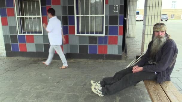 OLOMOUC, REPUBBLICA CECA, 5 MAGGIO 2018: Autentica emozione faccia senzatetto in città, lunga barba e sciarpa indiana tra i capelli, il povero sull'orlo della società, siede su una panchina e stampella invalida — Video Stock