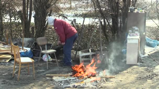 Olomouc, Tsjechië, januari 29, 2018: dakloze arme brandend hout bestuur panelen en creëren vuur om zichzelf warm in de wintersneeuw, vergelijkt dingen, wonen in een houten metalen chalet blad — Stockvideo