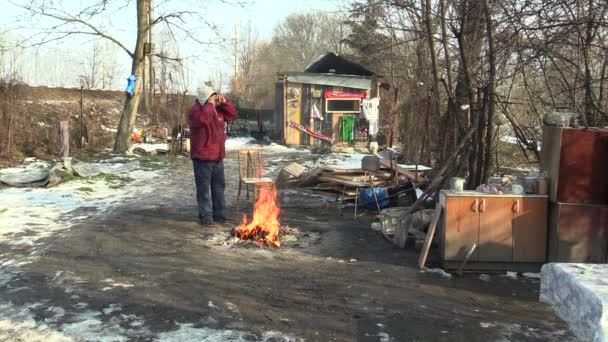 Olomouc, Cseh Köztársaság, 2018. január 29.: hajléktalan szegény égő fa tábla panelek és létrehozása a tüzet, hogy meleg magukat a téli hó, megtisztítani a szemed, élő-ban egy lapos fém fa faház — Stock videók