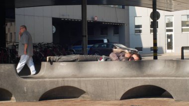 Ostrava, Çek Cumhuriyeti, 28 Ağustos 2018: otantik duygu evsiz adam bir tezgah ve yürüyen insanlar üzerinde uyuyor
