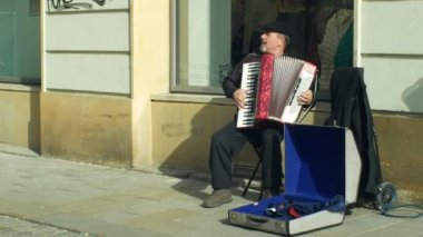 Olomouc, Çek Cumhuriyeti, 29 Ocak 2019: Çingene adam para bir bardağa otantik müzik akordeon mızıka çalıyor yalvarıyor şehirde insanlar kaldırım ve atmak para dilenci üzerinde yürümek